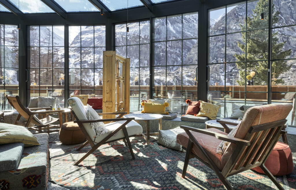 Cozy lounge with armchairs and large windows overlooking snow-covered mountains and trees, reminiscent of the serene alpine landscape in South Tyrol.